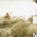 Around bend in railroad, buildings on either side.